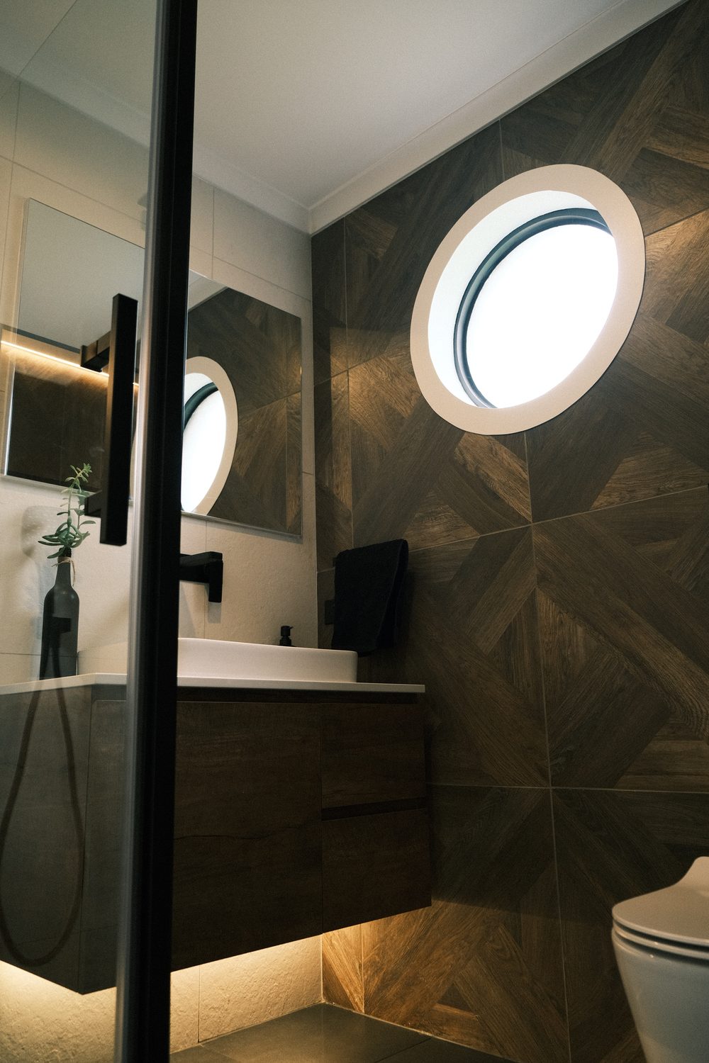The same ensuite, finished with a dark timber feature wall