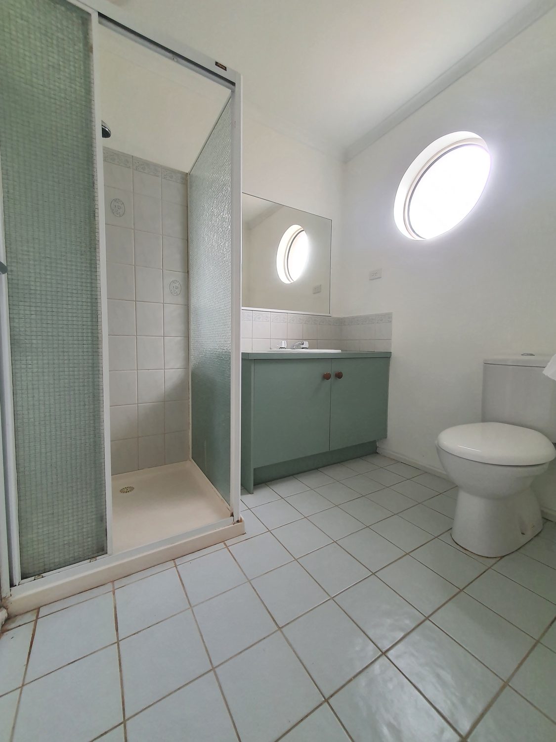 Dated ensuite before renovation, original green cabinetry