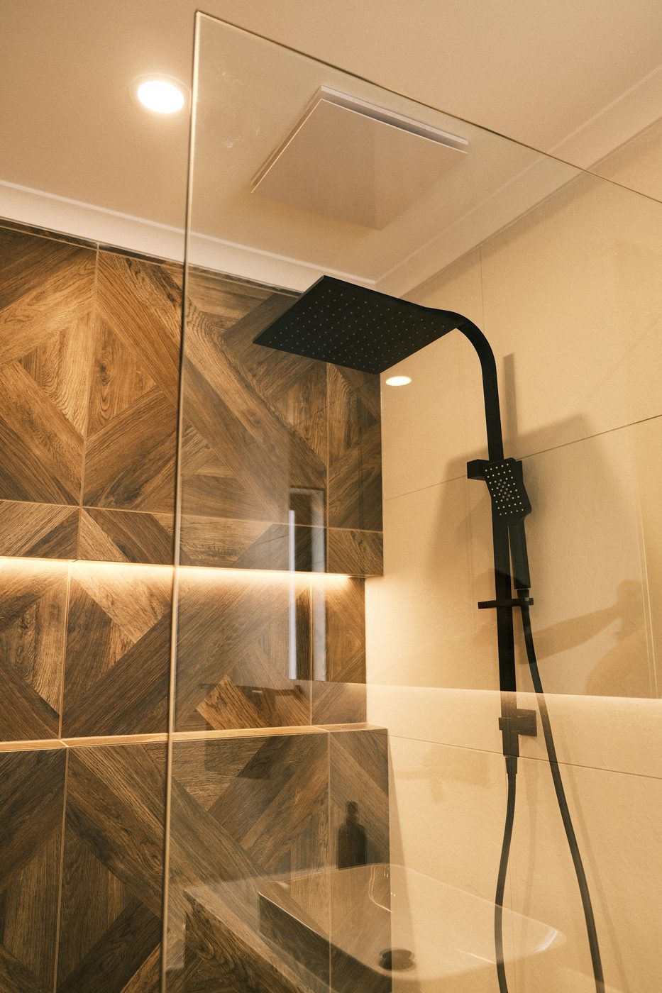 Matte-black rain shower against dark-timber parquet tiling, Berwick ensuite