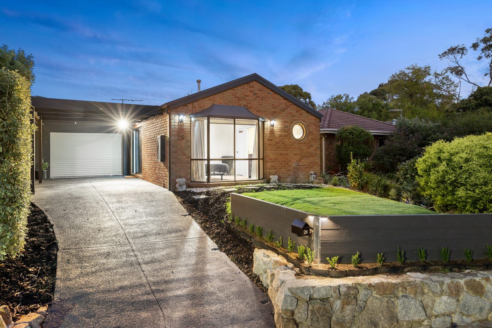 Brick home facade lit at dusk with landscaped front garden, Berwick